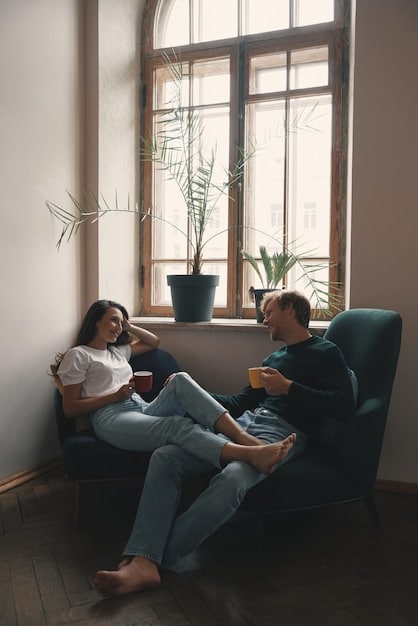 Two people sitting in a quiet, sunlit room, engaged in a deep conversation. One person is listening attentively, while the other is speaking with a calm and reassuring expression, suggesting a mentorship dynamic focused on emotional and spiritual support.