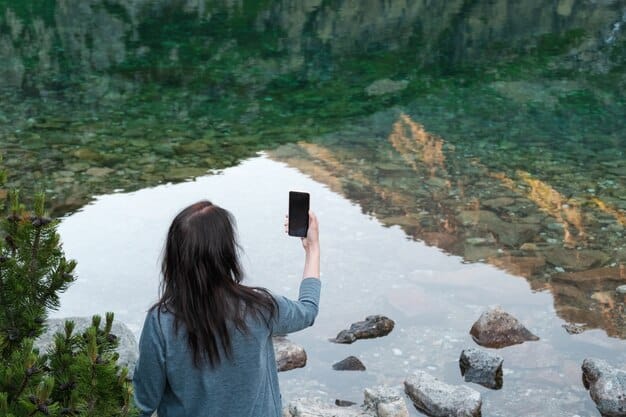 A person looking out over a scenic landscape, with their phone turned off and placed on a nearby rock, symbolizing a digital detox.