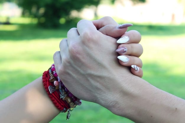 A close-up image of two hands clasped together, symbolizing trust and support in a spiritual mentorship relationship.