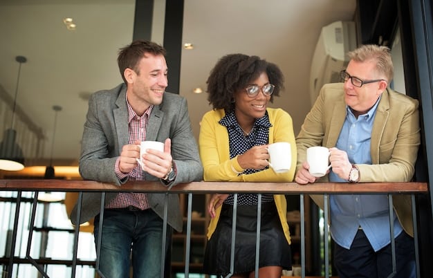 Diverse business colleagues smiling and laughing together during a casual meeting in a brightly lit office space, representing teamwork, camaraderie, and positive relationships.