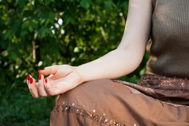 Close-up of a person's hands resting gently on their lap during meditation, with a blurred background of a peaceful garden.