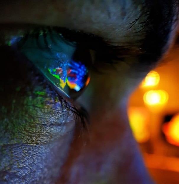 A close-up of a person's eye reflecting a kaleidoscope of colors and patterns, symbolizing the activation of imagination and creative thought during visualization meditation.