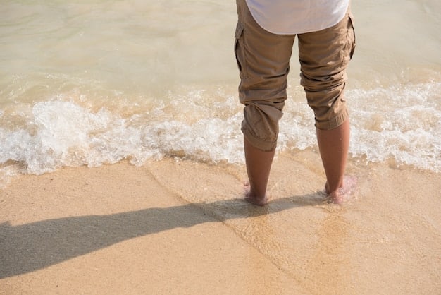 A person is walking barefoot on a sandy beach, focusing on each step they take. The ocean waves are gently lapping at the shore in the background, creating a tranquil and meditative atmosphere.