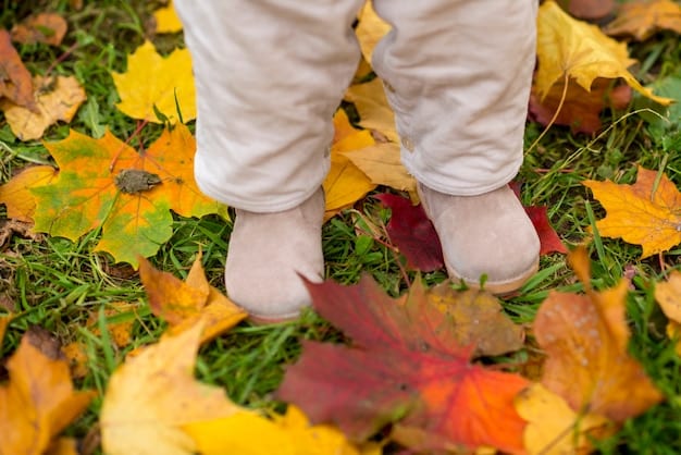 A close-up view of feet walking on a path covered with autumn leaves. The focus is on the texture and color of the leaves, highlighting the sensory experience of walking in nature.