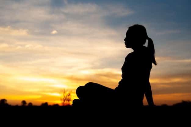 A silhouette of a person sitting in meditation pose at sunset, symbolizing overcoming challenges and achieving inner peace. The colors are warm and inviting.