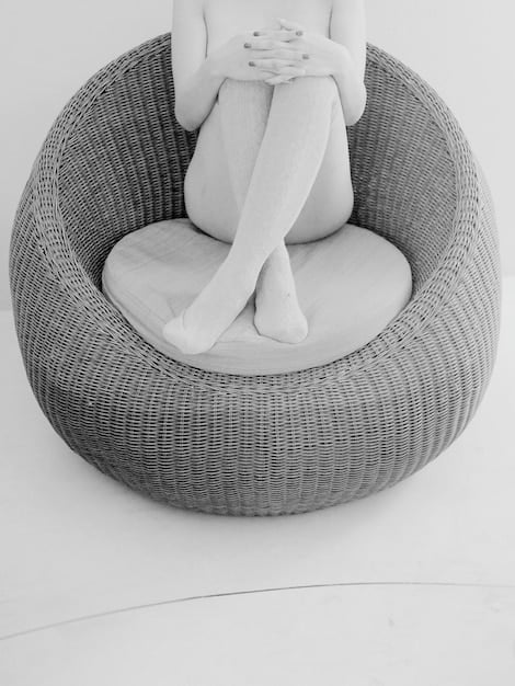 A person sitting comfortably on a meditation cushion in a minimalist room, eyes closed, with hands resting gently on their knees. Soft, natural light filters through a nearby window, creating a peaceful atmosphere.