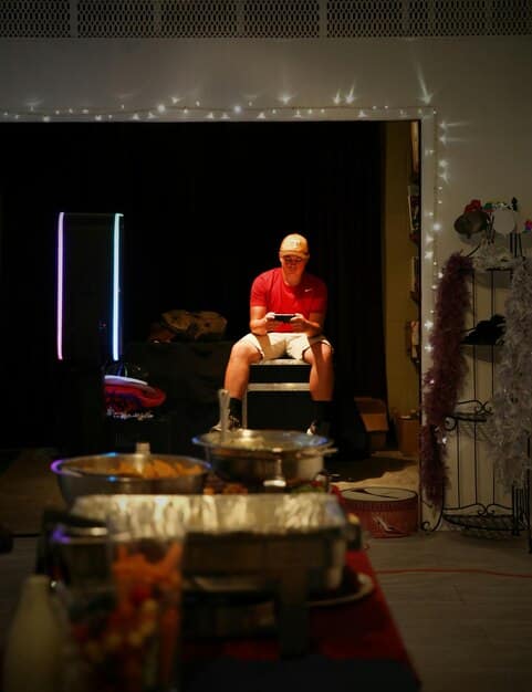 A person playing a large gong with a soft mallet in a dimly lit room with candles, creating a serene atmosphere. The person is dressed in comfortable clothing, and their expression shows concentration and peace.