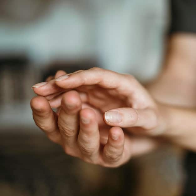 A close-up shot of a person's hands clasped together in a gesture of prayer or gratitude, with a soft, blurred background suggesting a peaceful environment.