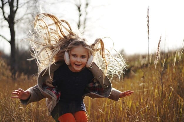 A playful image of a young Aries child, filled with energy, running outdoors with a determined expression, showcasing their natural leadership qualities.