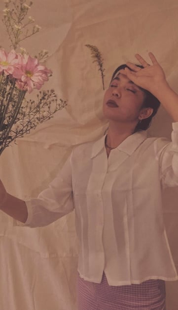 A person wearing soft, flowing clothing, embracing the vintage aesthetic through pieces such as a lace top and a floral skirt. The setting suggests a cozy home environment, further emphasizing the nurturing characteristics of Cancer.