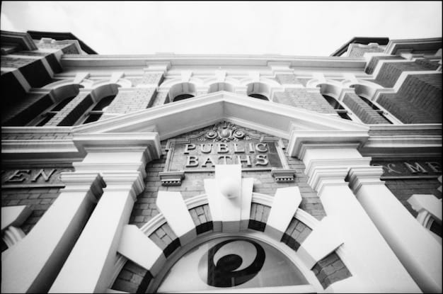 A split image contrasting two opposing scenarios: on one side, a traditional bank with a long queue of people, symbolizing conventional finance; on the other side, a futuristic digital interface with blockchain technology, representing innovative financial solutions. The contrast highlights the clash between traditional and modern financial systems during the Uranus in Taurus transit.