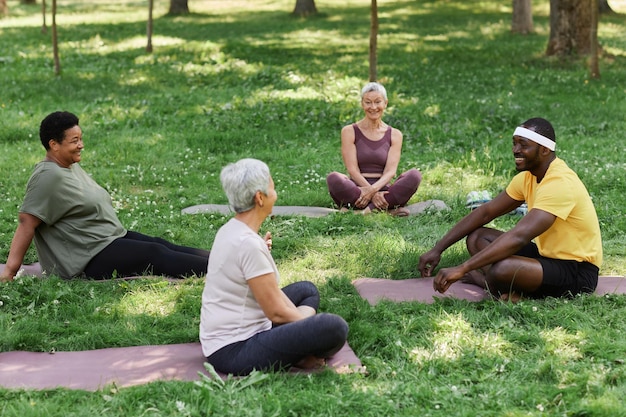 A diverse group of people participating in a yoga class outdoors, highlighting the communal and physical aspects of spiritual practices.