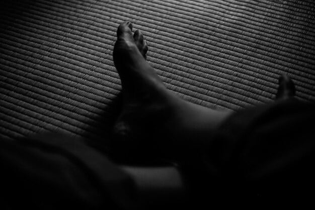 A close-up shot of feet resting on a yoga mat, symbolizing the beginning of a body scan meditation. The lighting is soft and the image conveys a sense of calm and grounding.