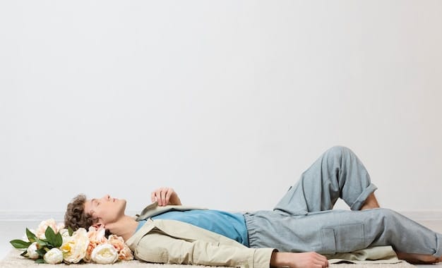 A person lying comfortably on their back with a blanket, eyes closed, hands slightly apart from the body, palms facing up. The background is a simple, softly colored wall in a quiet room.