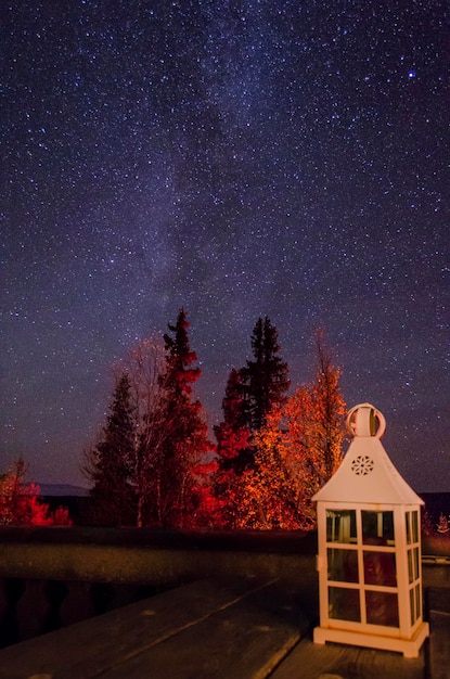 A photograph of the night sky over Cherry Springs State Park, showing the Milky Way galaxy stretching across the frame with visible stars and nebulae. Dark silhouettes of trees line the horizon.
