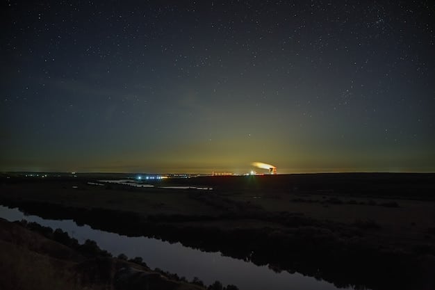 A wide-angle shot showing a dark, rural landscape in the US at night, with a faint comet visible low on the eastern horizon, as seen from the perspective of an observer with minimal light pollution.