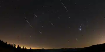 Quadrantid meteor shower streaks across a star-filled winter night sky, with constellations subtly visible.
