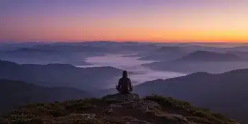 Figure meditating on a mountain at sunrise, symbolizing spiritual reset and inner peace.
